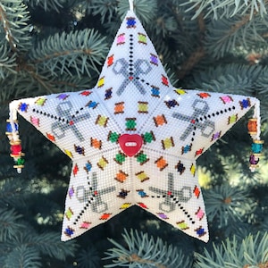 May include: A white, star-shaped Christmas ornament with a beaded design. The ornament features gray scissors, colorful thread spools, and a red heart-shaped button. It is decorated with colorful beads and a gold wire hanger.