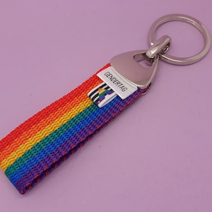 May include: A rainbow-coloured keychain with a silver key ring and a small white tag that says "GENDER TAG".