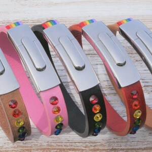 May include: Five leather bracelets in brown, pink, black, red, and tan. Each bracelet has a silver clasp and is decorated with colourful gemstones and a rainbow stripe.