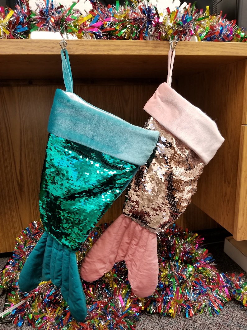 Whimsical Christmas stockings shaped like mermaid tails in green or pink velvet with matching sequins and can be personalized