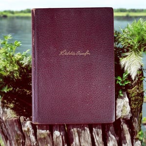 May include: A burgundy leather-bound book with the inscription "Ralph Waldo Emerson" on the front cover.