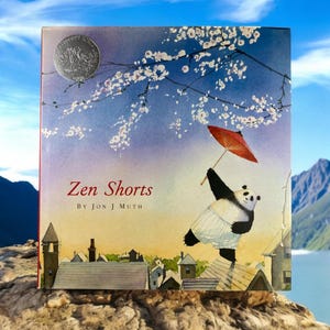 May include: A book titled "Zen Shorts" by Jon J Muth. The cover features a panda wearing shorts and holding a red umbrella, standing on a rooftop with a backdrop of a blue sky and cherry blossoms.