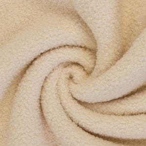Könnte beinhalten: Ein cremefarbener Stoff mit einer dichten, lockigen und strukturierten Oberfläche. Das Material ist in einem wirbelnden Spiralmuster angeordnet, das tiefe Falten und Schatten erzeugt und die dicke, flauschige und geschlungene Textur hervorhebt.