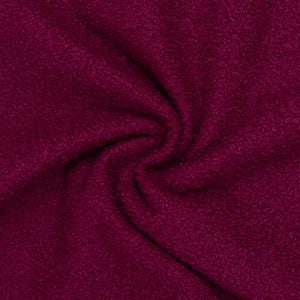 Könnte beinhalten: Ein tief magentafarbener Stoff mit einer dichten, lockigen und strukturierten Floroberfläche. Das Material ist in einem weichen Spiralmuster angeordnet, das die dicke, flauschige Konsistenz und die satte, gesättigte Farbe der Fasern betont.