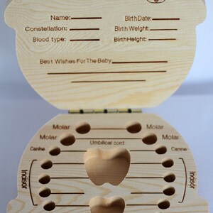 Puede incluir: Una caja de dientes de beb&eacute; de madera con una tapa con bisagras. La tapa tiene una secci&oacute;n para registrar la informaci&oacute;n del beb&eacute;, incluyendo el nombre, la fecha de nacimiento, el peso al nacer y la altura al nacer. La caja tiene un compartimento en forma de coraz&oacute;n para guardar el cord&oacute;n umbilical y una cuadr&iacute;cula de c&iacute;rculos para guardar los dientes de beb&eacute;. La caja est&aacute; etiquetada con las palabras "Molar", "Canine", "Incisor" y "Lanugo".