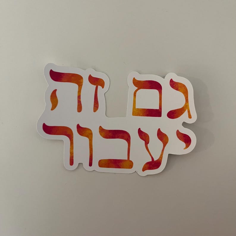 May include: A white sticker with Hebrew text in red and orange watercolor lettering. The sticker has a die-cut shape, with the text arranged in a curved layout. The background is a plain white surface.