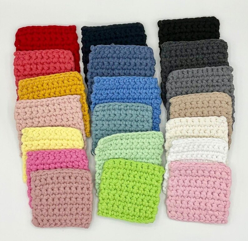 K&ouml;nnte beinhalten: Eine Sammlung von 20 geh&auml;kelten Quadraten in verschiedenen Farben, darunter Rot, Rosa, Gelb, Gr&uuml;n, Blau, Grau und Wei&szlig;. Die Quadrate sind in Reihen angeordnet und alle gleich gro&szlig;.