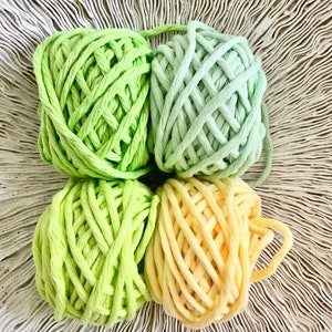 K&ouml;nnte beinhalten: Vier Kn&auml;uel Garn in Gr&uuml;n- und Gelbt&ouml;nen. Das Garn ist dick und robust, perfekt zum H&auml;keln oder Stricken.