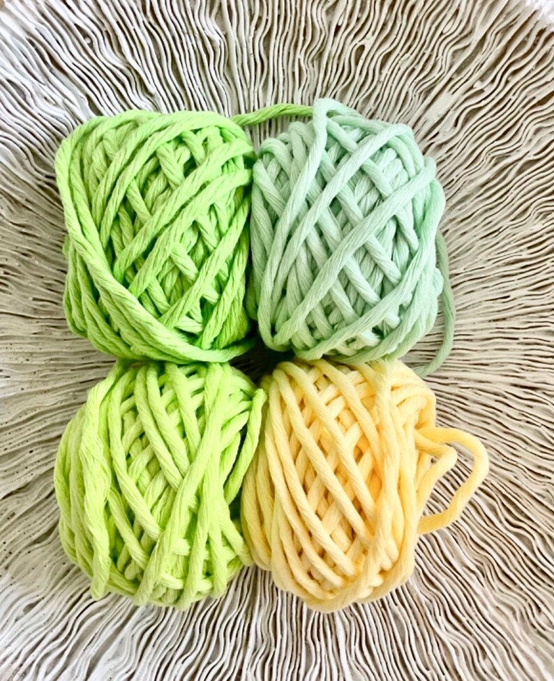 K&ouml;nnte beinhalten: Vier Kn&auml;uel Garn in Gr&uuml;n- und Gelbt&ouml;nen. Das Garn ist dick und robust, perfekt zum H&auml;keln oder Stricken.