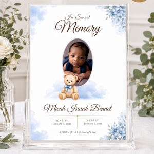 May include: A bi-fold funeral program template measuring 11 inches by 8.5 inches. The design features blue watercolor flowers, a central oval photo frame, a teddy bear illustration, and text reading In Sweet Memory, Micah Isaiah Bennet.