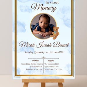 May include: A memorial sign with a baby's photo, text "In Sweet Memory", and the name "Micah Isaiah Bennet". The sign is on a wooden easel. The background has a blue watercolor design and gold trim.