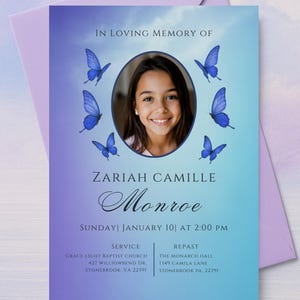 May include: A memorial card with a photo of a smiling girl, surrounded by blue butterflies, set against a gradient blue and purple background. Text includes "In Loving Memory of Zariah Camille Monroe".