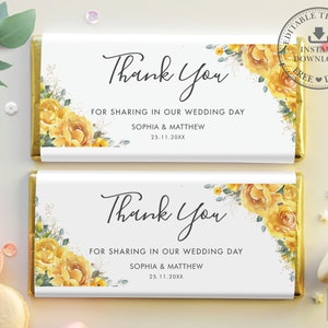 Könnte beinhalten: Zwei weiße Schokoladenriegelverpackungen mit goldenen Folienakzenten. Die Verpackungen zeigen ein Aquarell-Blumendesign mit gelben Rosen und grünen Blättern. Der Text auf den Verpackungen lautet "Vielen Dank" und "Für die Teilnahme an unserem Hochzeitstag, Sophia & Matthew, 25.11.20XX".