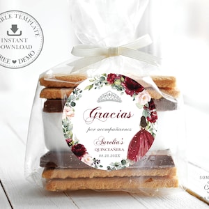May include: A round favor tag with a floral design in shades of burgundy and white. The tag features a tiara, a girl in a burgundy dress, and the text "Gracias por acompa&ntilde;arnos Aurelia's Quincea&ntilde;era 08.25.20XX".