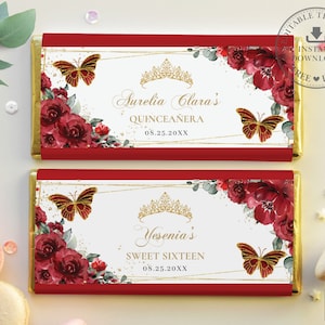 May include: Two red and white chocolate bar wrappers with gold accents. The top wrapper has the text "Aurelia Clara's Quinceañera 08.25.20XX". The bottom wrapper has the text "Yesenia's Sweet Sixteen 08.25.20XX". Both wrappers feature a gold crown, red roses, and butterflies.
