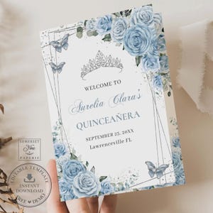 May include: A light blue and silver Quinceañera invitation with a floral design featuring blue roses, butterflies, and a silver crown. The text reads "Welcome to Surelia Clara's Quinceañera, September 25, 20XX, Lawrenceville FL."