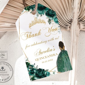 Può includere: Un'etichetta di ringraziamento dorata e verde con un design floreale e una corona. L'etichetta dice "Grazie per aver festeggiato con noi! Quinceañera di Aurelia 08.25.20XX".