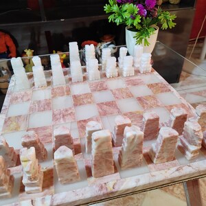 Pu&ograve; includere: Un set di scacchi in marmo bianco con scacchiera a scacchi rosa e bianca. I pezzi degli scacchi sono scolpiti in uno stile unico e la scacchiera &egrave; realizzata in un bellissimo marmo.