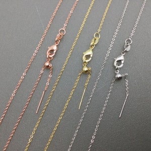 May include: Four adjustable necklace chains in silver, gold, and rose gold. Each chain has a small bead and a sliding clasp.