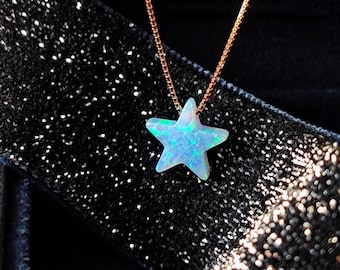 May include: A silver chain necklace with a blue iridescent star-shaped pendant. The pendant is made of opal and has a sparkly finish.