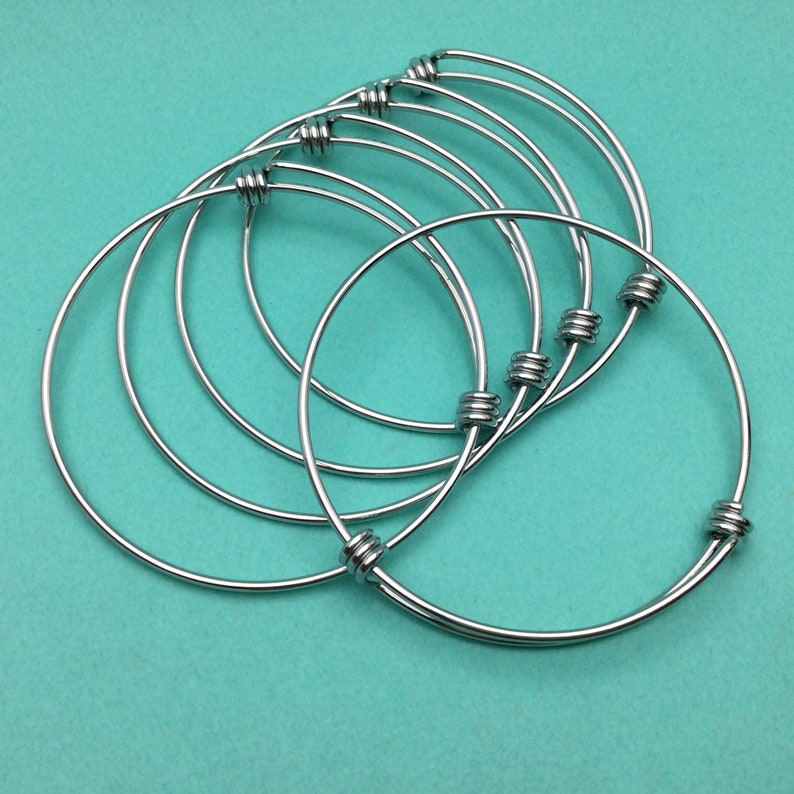 May include: Set of six silver bangle bracelets with a knotted design. The bracelets are stacked on top of each other.