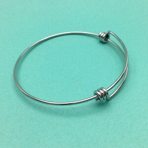 May include: A silver expandable bangle bracelet with a twisted wire design.