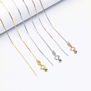 May include: Six different chain necklaces in gold, silver, and rose gold. The chains are all the same length and have a box clasp.