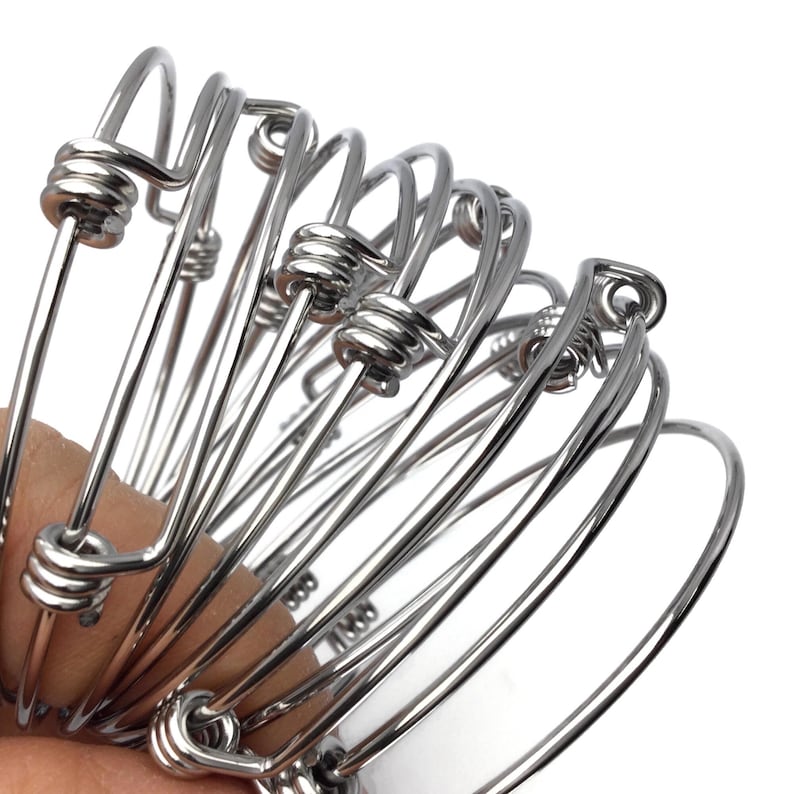 May include: A set of silver-toned bangle bracelets with a twisted wire design. The bracelets are stacked on top of each other.