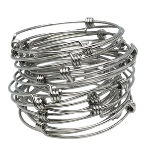 May include: A stack of silver wire bangle bracelets. The bracelets are simple and elegant, with a twisted wire design.