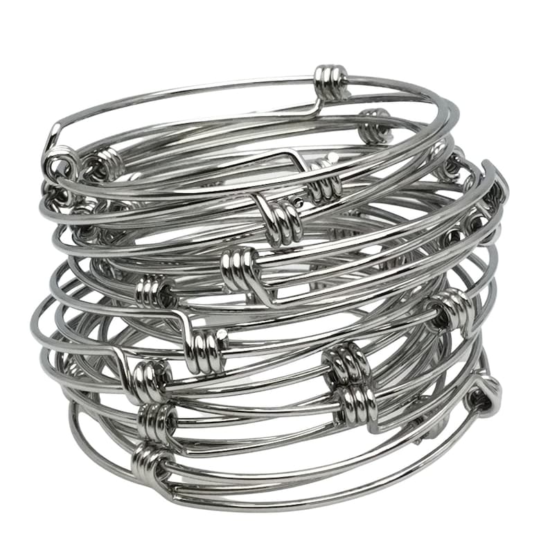 May include: A stack of silver wire bangle bracelets. The bracelets are simple and elegant, with a twisted wire design.