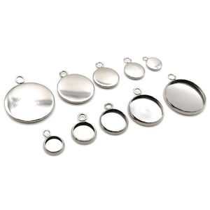 May include: Assortment of silver-toned metal pendant trays with round bezels and loops for hanging. The trays are of various sizes.