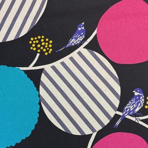 Könnte beinhalten: Stoffmuster mit schwarzem Hintergrund, mit großen rosa und blauen Kreisen, gestreiften Kreisen und kleinen gelben Blütengruppen. Blaue Vögel sitzen auf weißen, geschwungenen Linien. Das Muster wiederholt sich.