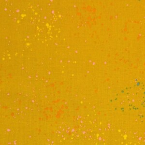 Könnte beinhalten: Senfgelber Stoff mit einem gesprenkelten Muster. Der Stoff ist mit kleinen, unregelmäßigen Punkten in Rosa, Orange, Gelb und Türkis bedeckt. Der Gesamteffekt ist ein verspieltes, strukturiertes Design.