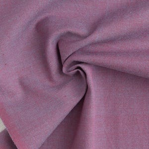 Könnte beinhalten: Nahaufnahme eines gefalteten Stoffes in Lila- und Rosatönen. Der Stoff hat eine gewebte Textur, mit sichtbaren Fäden, die ein subtiles Muster bilden. Die Falten erzeugen Schatten und Tiefe und heben die Textur und Farbvariationen des Stoffes hervor.