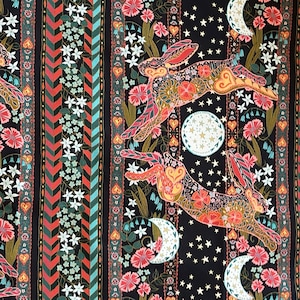 Könnte beinhalten: Schwarzer Stoff mit einem sich wiederholenden Muster aus stilisierten Hasen, Mondsicheln und floralen Designs. Die Hasen sind in Orange-, Rosa- und Grüntönen dargestellt, die floralen Designs in Rosa-, Grün- und Weißtönen.