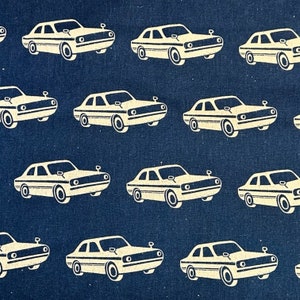 Könnte beinhalten: Ein sich wiederholendes Muster aus weißen Autos auf dunkelblauem Hintergrund. Die Autos sind alle in die gleiche Richtung ausgerichtet und haben ein schlichtes, vintage-Design.