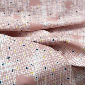 Könnte beinhalten: Rosafarbener Stoff mit einem weißen Gittermuster und kleinen gelben und blauen Quadraten. Der Stoff ist gefaltet und strukturiert.