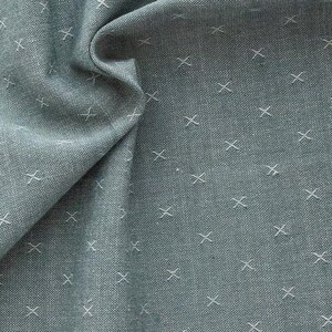 Könnte beinhalten: Nahaufnahme eines hellblauen Stoffes mit einem weißen Kreuzstichmuster. Der Stoff hat einen braunen Rand.