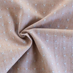 Könnte beinhalten: Nahaufnahme eines hellbraunen Stoffes mit einem weißen Herzmuster. Der Stoff ist strukturiert und hat einen dezenten Glanz. Der Text "FABLEISM" ist in der rechten unteren Ecke sichtbar.