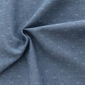 Könnte beinhalten: Nahaufnahme eines blauen Stoffes mit einem weißen Kreuzmuster. Der Stoff hat einen braunen Rand und der Text "FABLEISM" ist in der Mitte unten im Bild sichtbar.