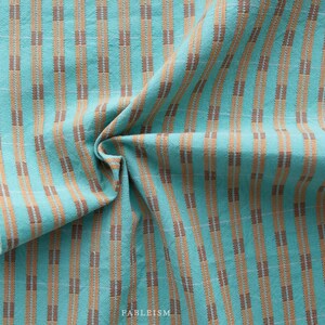 Könnte beinhalten: Tealfarbener und brauner gestreifter Stoff mit einer gewebten Textur. Der Stoff ist gefaltet und zeigt das Muster.