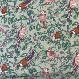 Könnte beinhalten: Ein grüner Stoff mit einem sich wiederholenden Muster aus rosa Vögeln und grünen Blättern. Die Vögel sind stilisiert und haben ein einfaches Design.