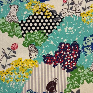 Könnte beinhalten: Ein farbenfrohes Stoffmuster mit einem Geparden, einem Hirsch, einer Eule und einem Lemuren inmitten stilisierter Blumen und Blätter. Das Design umfasst Polka Dots, Streifen und florale Elemente in Blau-, Gelb-, Rot- und Grüntönen auf cremefarbenem Hintergrund.