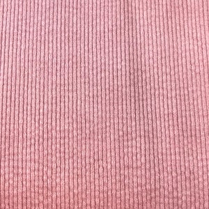 Puede incluir: Primer plano de una tela de color rosa con textura suave y superficie acanalada.