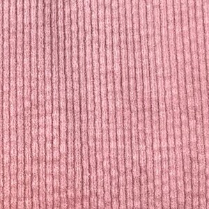Puede incluir: Primer plano de una tela de pana rosa con una textura acanalada vertical.
