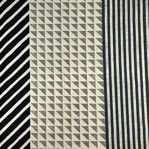 Könnte beinhalten: Ein Stoffmuster mit drei verschiedenen Mustern. Die linke Seite ist ein schwarz-weißes diagonales Streifenmuster. Die Mitte ist ein beige-graues geometrisches Muster aus Dreiecken. Die rechte Seite ist ein schwarz-weißes vertikales Streifenmuster.