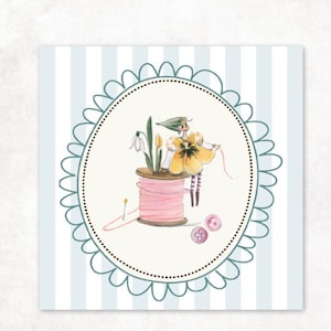 Könnte beinhalten: Eine skurrile Illustration mit einer feenhaften Figur in einem gelben Blumenkleid, die auf einer rosa Garnrolle steht. Das Bild ist in einem ovalen Rahmen mit Muschelrändern vor einem gestreiften Hintergrund mit Nähutensilien wie Knöpfen und einer Nadel angeordnet.