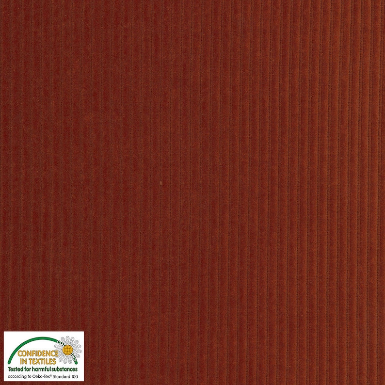 May include: Close-up of a textured, rust-colored corduroy fabric. The fabric has vertical ridges and a soft, velvety appearance. The image includes a "Confidence in Textiles" label.