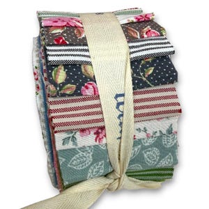 Könnte beinhalten: Ein Stapel Stoffquadrate in verschiedenen floralen und gemusterten Designs, gebunden mit einem cremefarbenen Band. Die Stoffe zeigen rosa Rosen, Tupfen und Streifen in Grau-, Rot- und Grüntönen. Das Band hat Text aufgedruckt.