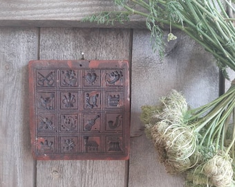 Op de afbeelding: Een vintage bruine keramische koekjesvorm met een raster van 16 verschillende ontwerpen. De vorm is gemaakt van een getextureerd materiaal en heeft een rustieke uitstraling.